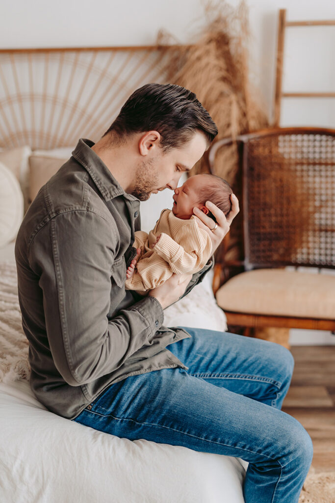 A dad holding his newborn son nose to nose.