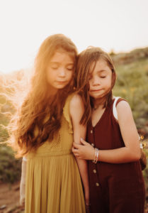 family photography, two sisters are leaning into each other with their eyes closed