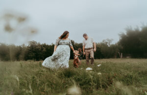 family photography, family is walking holding hands in a field.